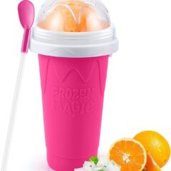 Roze Frozen Magic slush beker met deksel en lepel, naast ijsblokjes en vers gesneden sinaasappel.