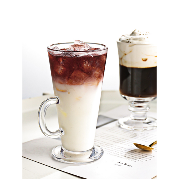 Iced latte met melk en koffie, geserveerd in een glas op een tafel, naast een donker kopje koffie met slagroom.
