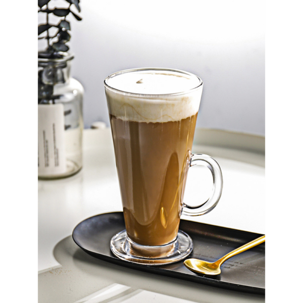 Hoge latte macchiato in glas op zwart dienblad met gouden lepel, perfect voor koffie-ontbijt in stijlvolle setting.