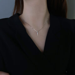 Elegant zilveren halsketting op zwarte jurk, minimalistische stijlaccessoire voor moderne vrouwen.