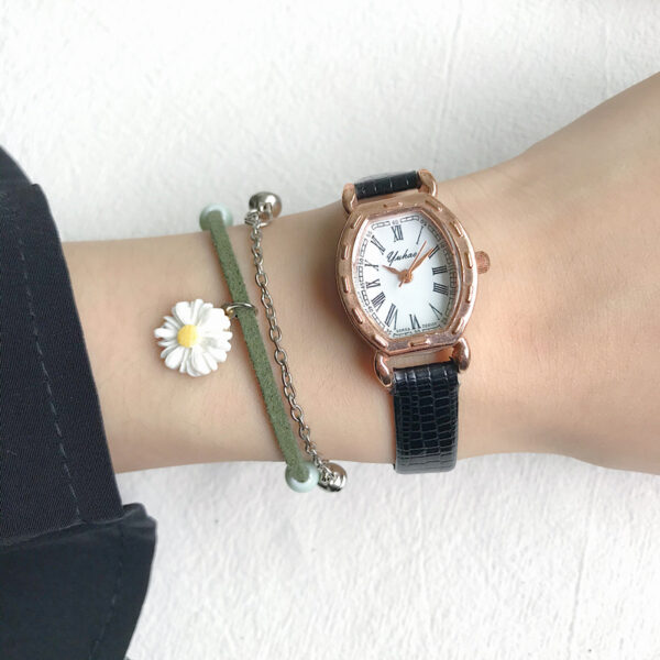 Klassiek horloge met zwart lederen band en bloemarmband om een pols, stijlvolle accessoire look.