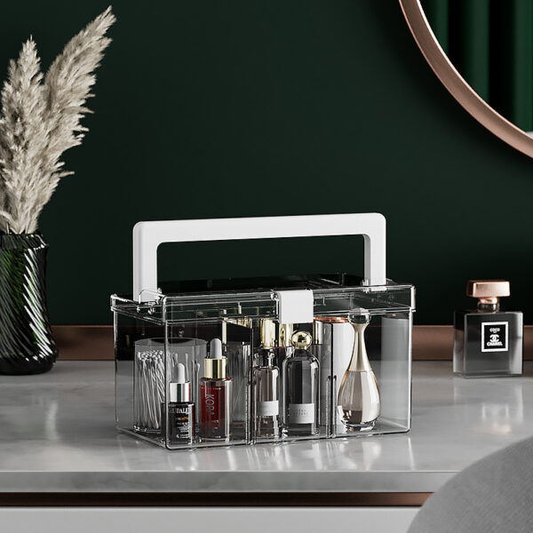 Transparante make-up organizer met handvat op een marmeren tafel, gevuld met diverse cosmetica en parfums, groene achtergrond.