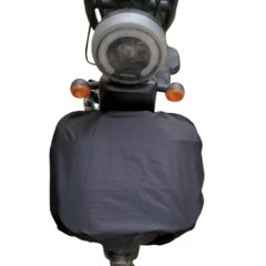 Klassieke motorfiets met zicht op koplamp en stuur, met een beschermhoes over het voorwiel, tegen een witte achtergrond.