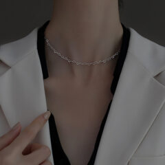Elegante zilveren ketting gedragen met een witte blazer, benadrukt stijl en verfijning.