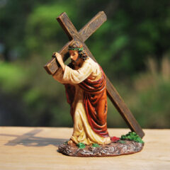 Beeld van een figuur die een houten kruis draagt in een symbolische religieuze context, buiten gefotografeerd.