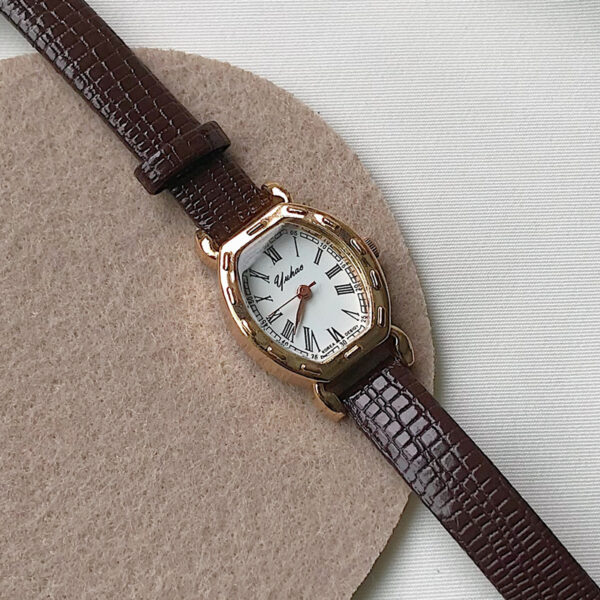 Retro horloge met bruin leren band en goudkleurige wijzerplaat, stijlvol en klassiek design.