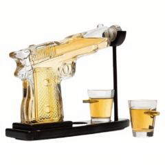 Glazen pistoolvormige karaf met drank en twee shotglaasjes op standaard, uniek whisky geschenkidee.