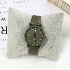 Olijfgroen horloge met leren band op een kussen, elegante tijdweergave, ideaal als modieus accessoire.