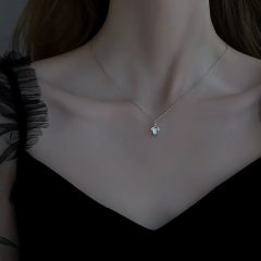 Dame met elegant zilveren ketting en zwart off-shoulder jurkje. Stijlvol en minimalistisch ontwerp voor elke gelegenheid.
