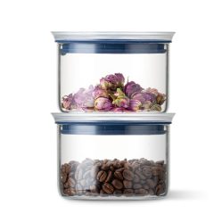 Stapelflessen met gedroogde bloemen bovenop en koffiebonen onderin, bewaard in glazen potten met blauwe deksels.