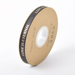 Rol zwart lint met tekst LOVE IS ETERNAL op kartonnen spoel, ideale decoratie voor cadeauverpakking.
