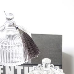 Kristallen sieradendoos met kwastje op zwart boek, stijlvolle en elegante decoratie.