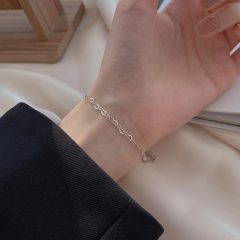 Zilveren armband met hartjesdetails om de pols op een elegante zijde achtergrond.