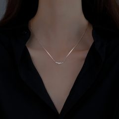 Elegante zilverkleurige halsketting met subtiele details op een vrouw in een zwarte blouse.