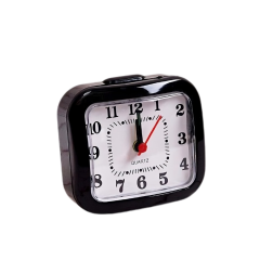 Zwarte analoge wekker met wijzers op 12 uur tegen een zwarte achtergrond.