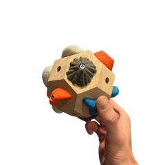 Houten klimgreep met kleurrijke hoekstukken, vastgehouden door een hand. Ideaal voor klimsporttraining.